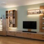Schreinermöbel in Eiche, schwarzen Griffen, Beton-Optik und variabler LED-Beleuchtung vor salbeigrün gestrichener Wand