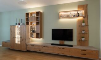 Schreinermöbel in Eiche, schwarzen Griffen, Beton-Optik und variabler LED-Beleuchtung vor salbeigrün gestrichener Wand